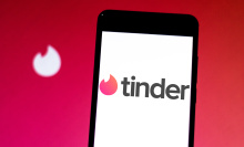 tinder logo on iphone in front of backdrop of tinder fire emblem