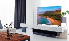 TCL TV with coastline screensaver on TV stand around other living room furniture