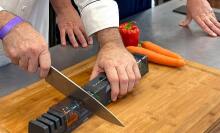 hands sharpening knife on a cutting board