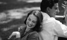 A woman leans on a man's back, both smiling, in a black and white film still.