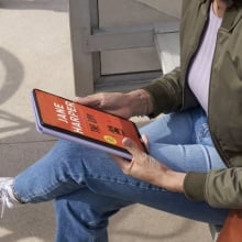 person sitting on a bench and reading a book on their fire max 11