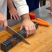 hands sharpening knife on a cutting board