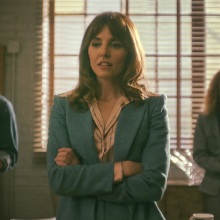 A woman in a blue suit with her arms crossed.
