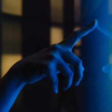 A hand touches a glowing blue screen.