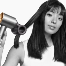 women uses dyson supersonic with flyaway smoother attachment to blow dry her hair