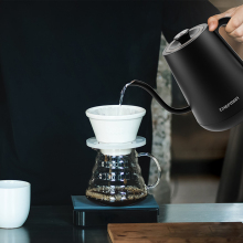 The Chefman gooseneck kettle held up by someone over a filter coffee maker in a kitchen.