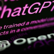 ChatGPT website displayed on a laptop screen and OpenAI logo displayed on a phone screen.