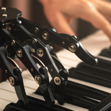 a robotic hand and a human hand playing a piano together