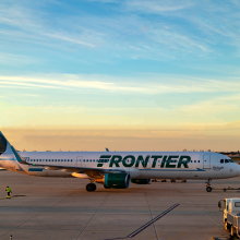 Frontier plane on ground at airport with sunset in background