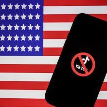 Logo of Tiktok is displayed on mobile phone screen in front of flag of United States, in Ankara, Turkiye on April 20, 2023.