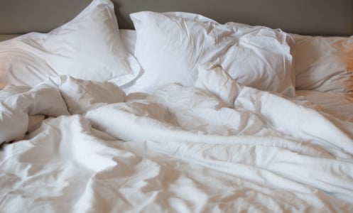 A close-up view of messy bed with comforter and pillows