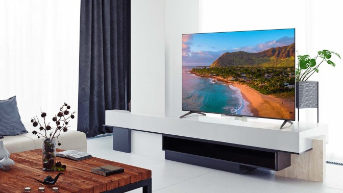 TCL TV with coastline screensaver on TV stand around other living room furniture