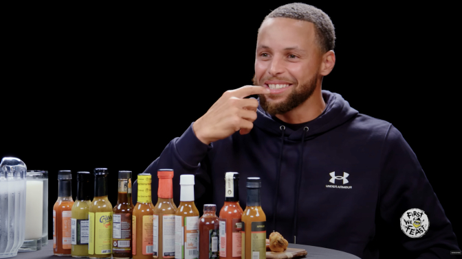 Steph Curry smiles and points to his mouth on "Hot Ones" 