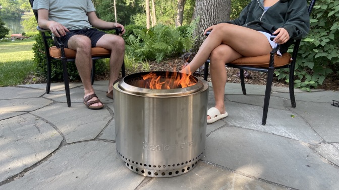 two people sitting around a solo stove bonfire 2.0 on a stone patio