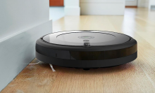Roomba cleaning along the edge of a wall on a wooden floor