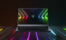 a razer blade 15 gaming laptop sitting on a surface embedded with colorful striped lights against a black background