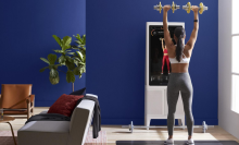 Person lifting dumbbells following workout on Tempo Studio fitness mirror in living room
