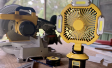 The Q-Beam Cyclone Combination Rechargeable LED Work Light & Fan standing on a work table surrounded by other tools