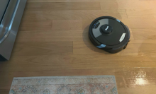 Black robot vacuum on hardwood floor.