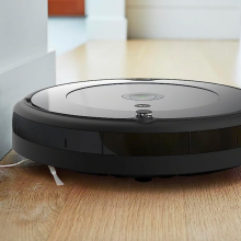 Roomba cleaning along the edge of a wall on a wooden floor