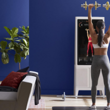 Person lifting dumbbells following workout on Tempo Studio fitness mirror in living room