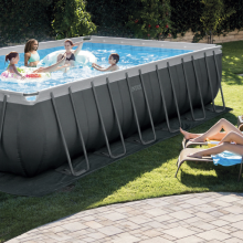 The Intex Ultra XTR pool standing on someone's lawn, with people swimming in it while others sunbathe nearby