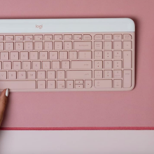 pastel pink wireless mouse and keyboard with hands on each item