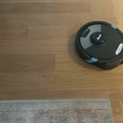 Black robot vacuum on hardwood floor.